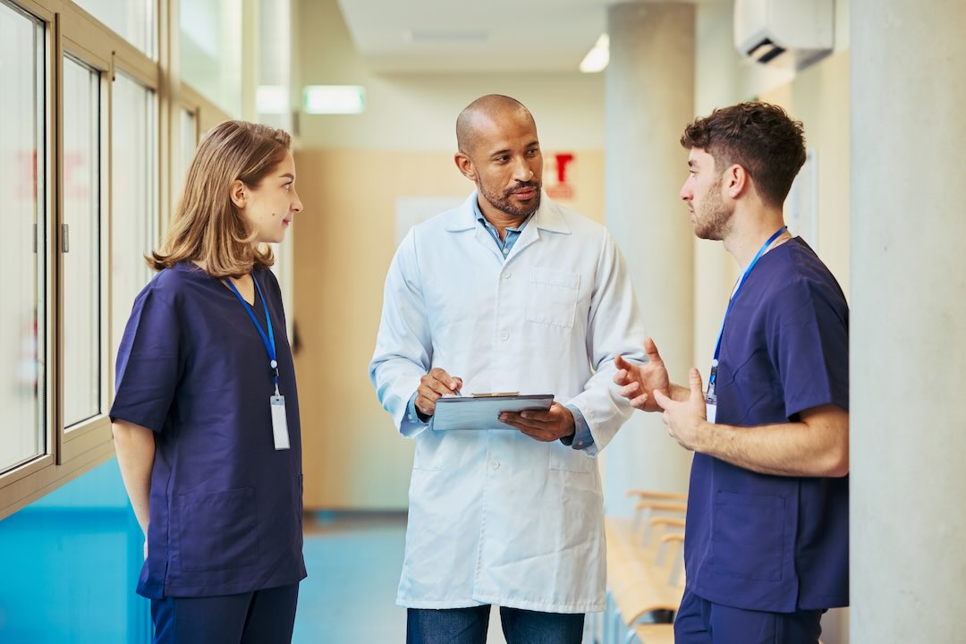 A doctor in discussion with two nurses in the hospital hallways