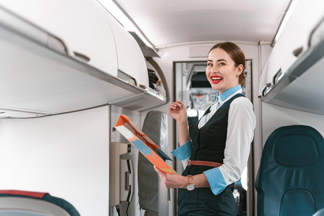 Female flight attendant checking the overhead bag compartments