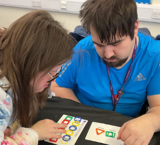 Two students playing a board game with shapes