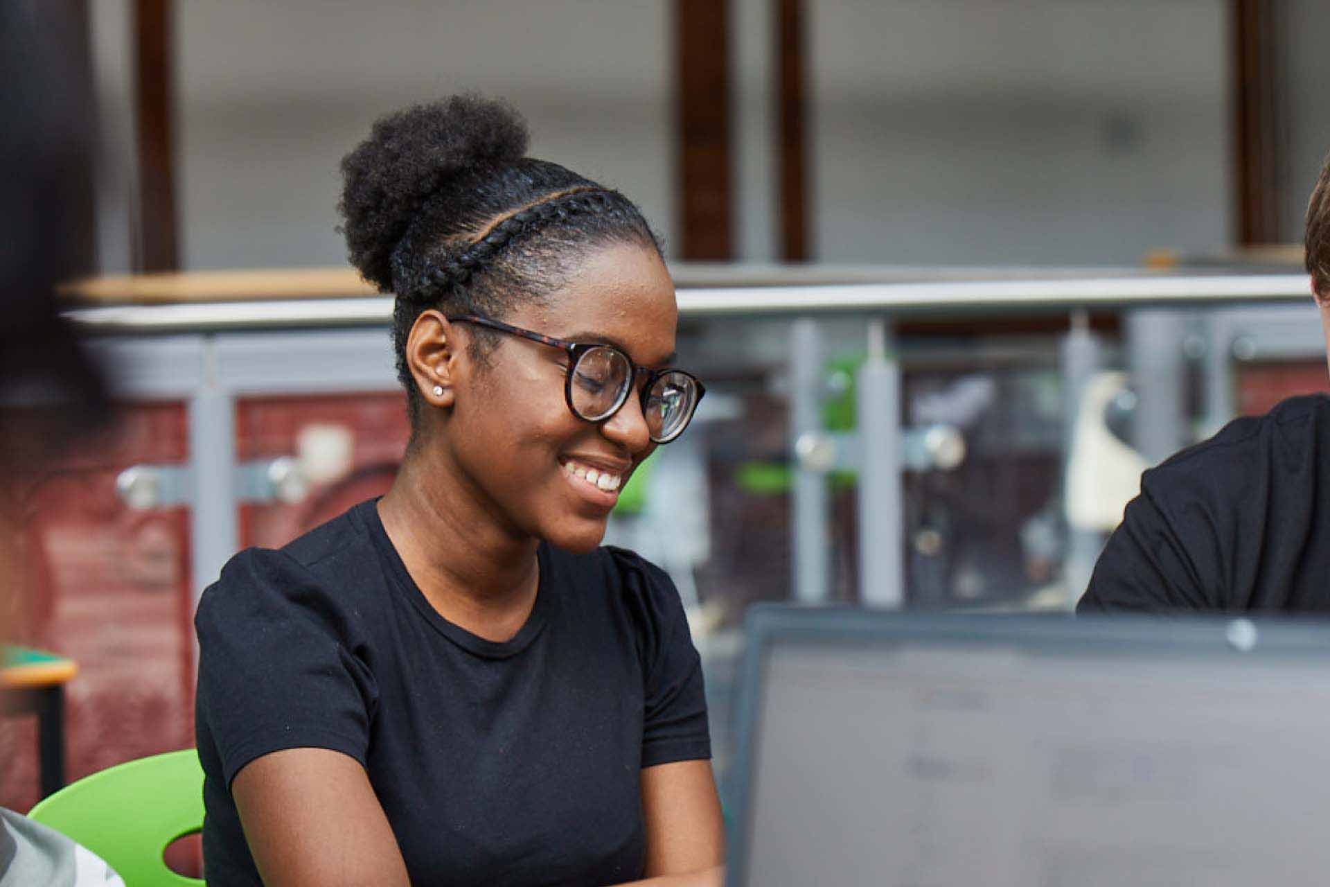 A smiling female student with glasses working on a computer
