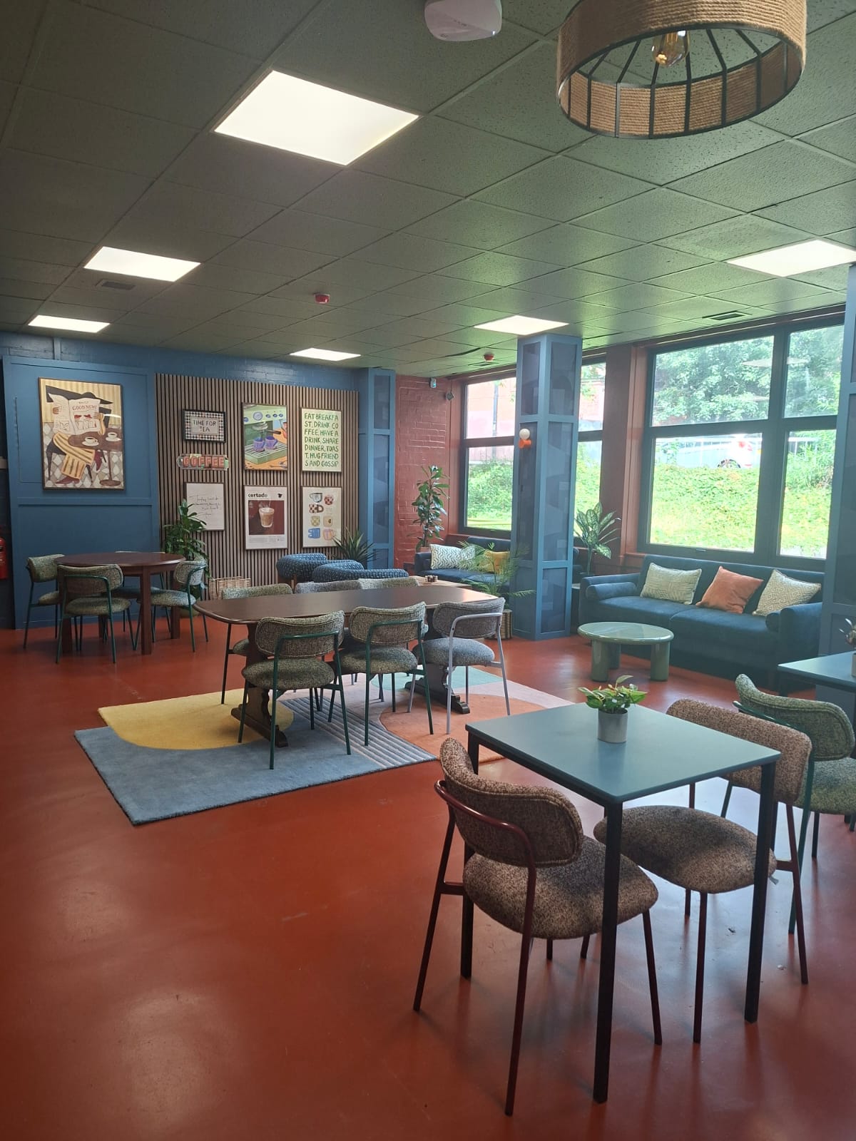 Modern cafe seating area with blue panelled walls, terracotta floors, and various dining and lounge tables.
