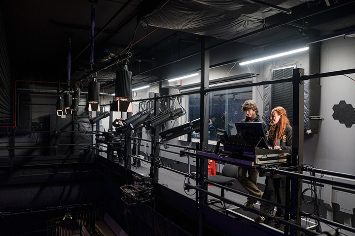 Two people stood backstage controlling on stage lighting