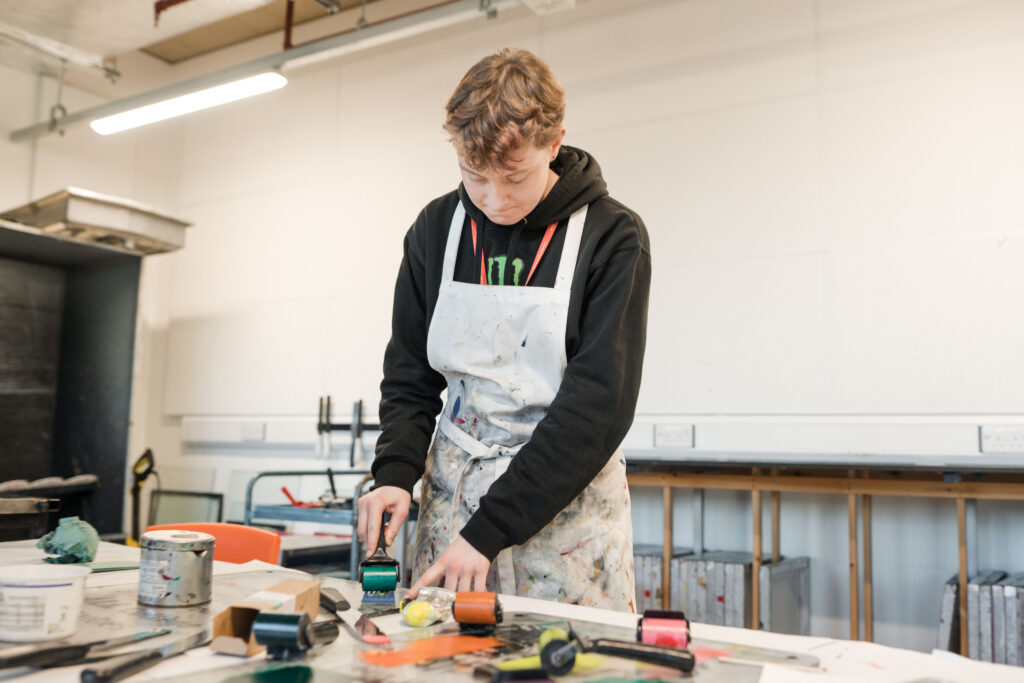 Student using a rolling printer to make designs