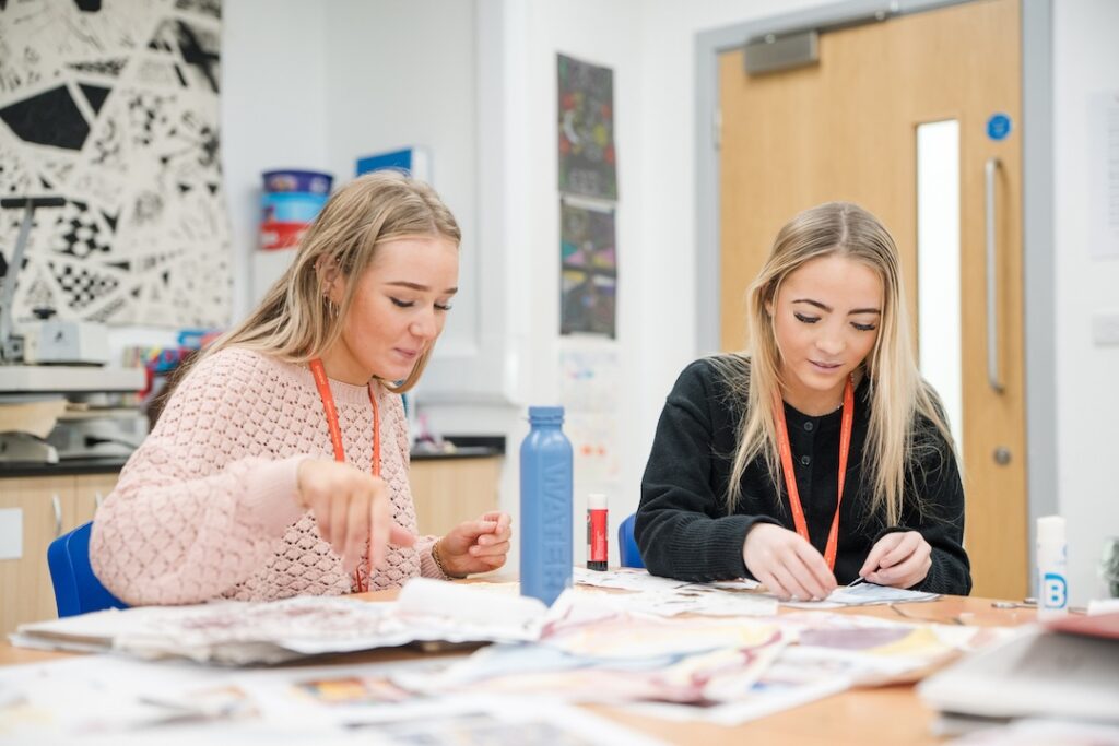 Two students sticking fashion design ideas onto a mood board