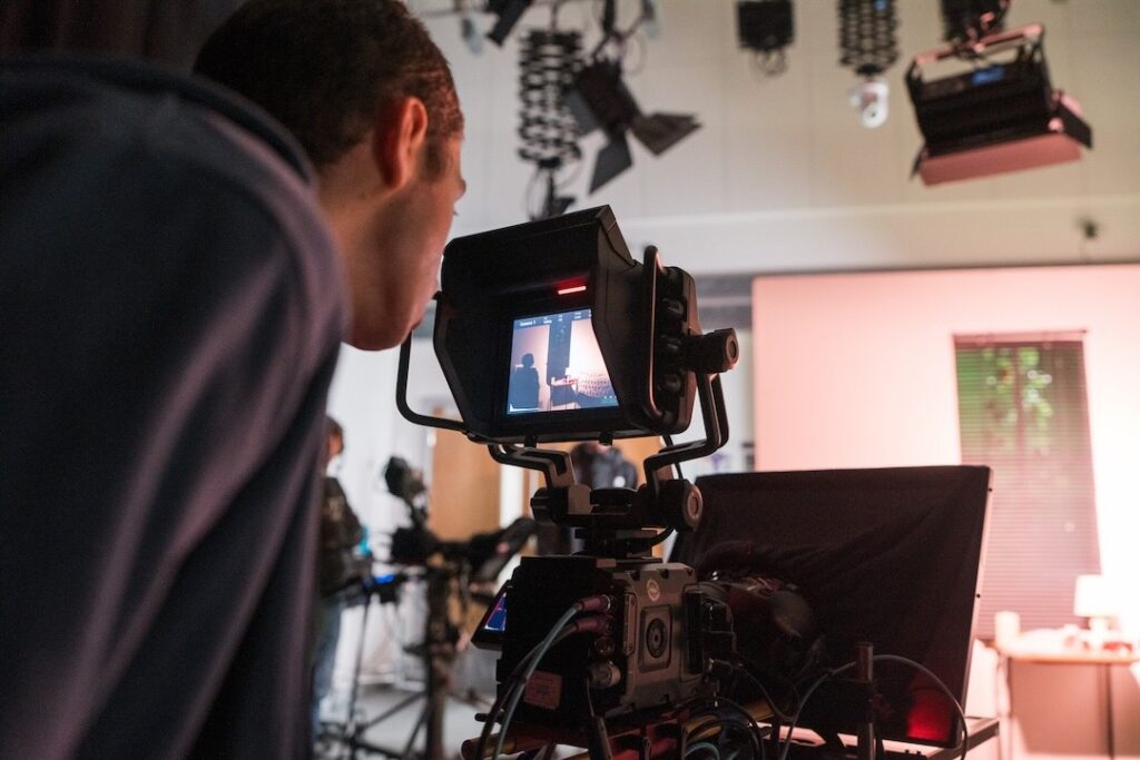 A student looking through the viewfinder screen of a large studio camera