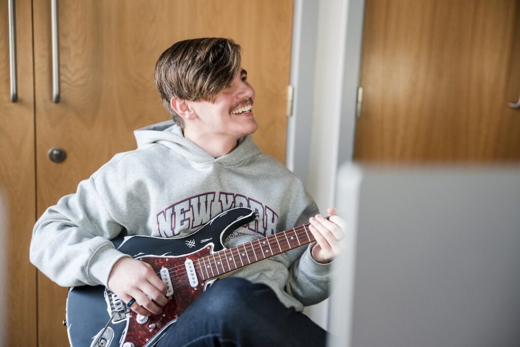 Student sat playing guitar