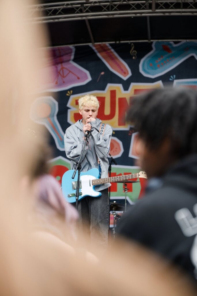 Student performing live on stage singing and playing the guitar