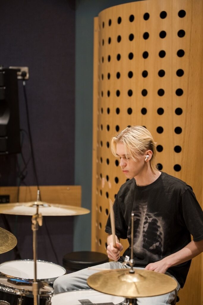 Student playing the drums in a recording studio