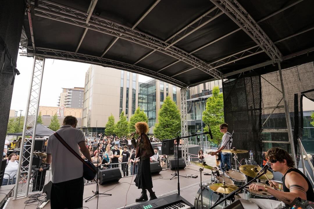 A band of students performing outside of quarry hill on the outdoor stage