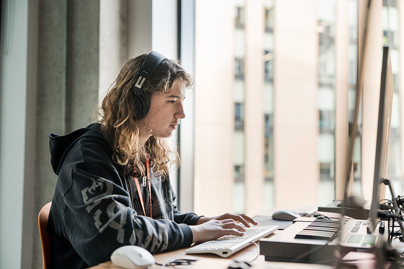 Person sat working on music technology with headphones on