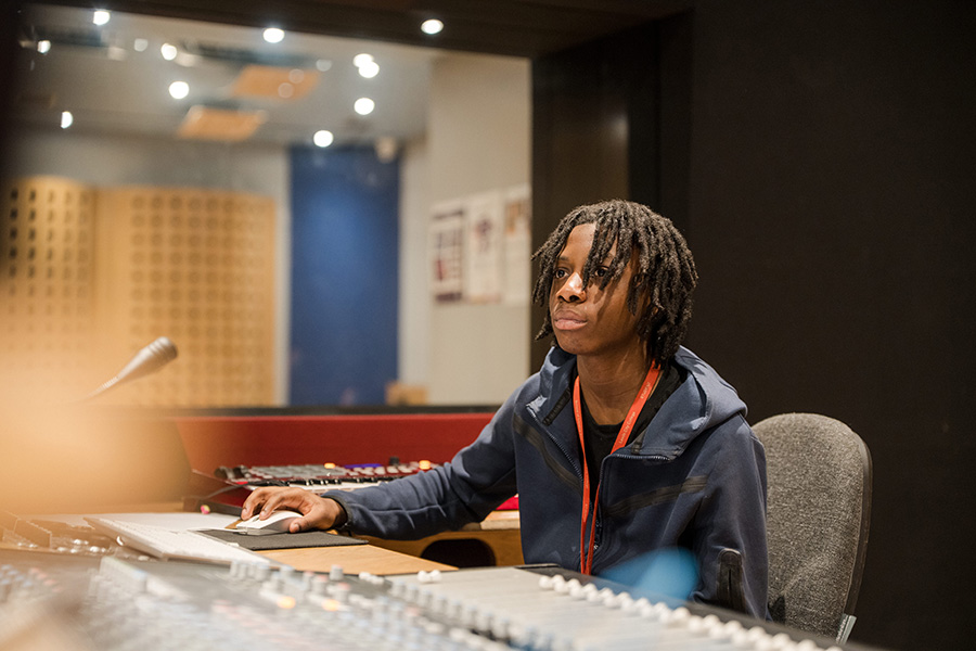 Person sat in recording studio working on sound equipment