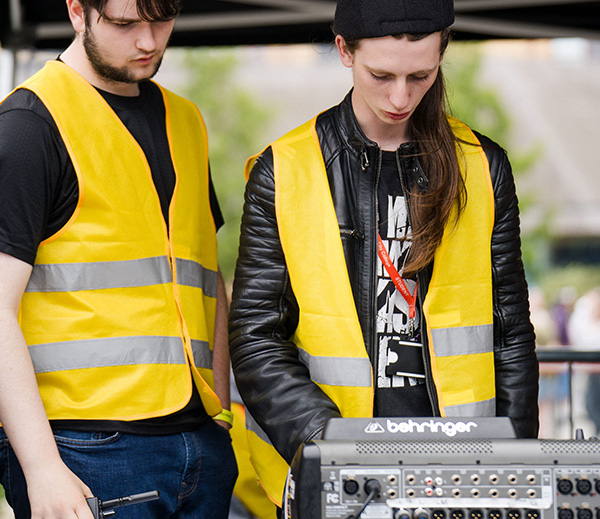 Students in high vis jackets working on sound equipment on stage